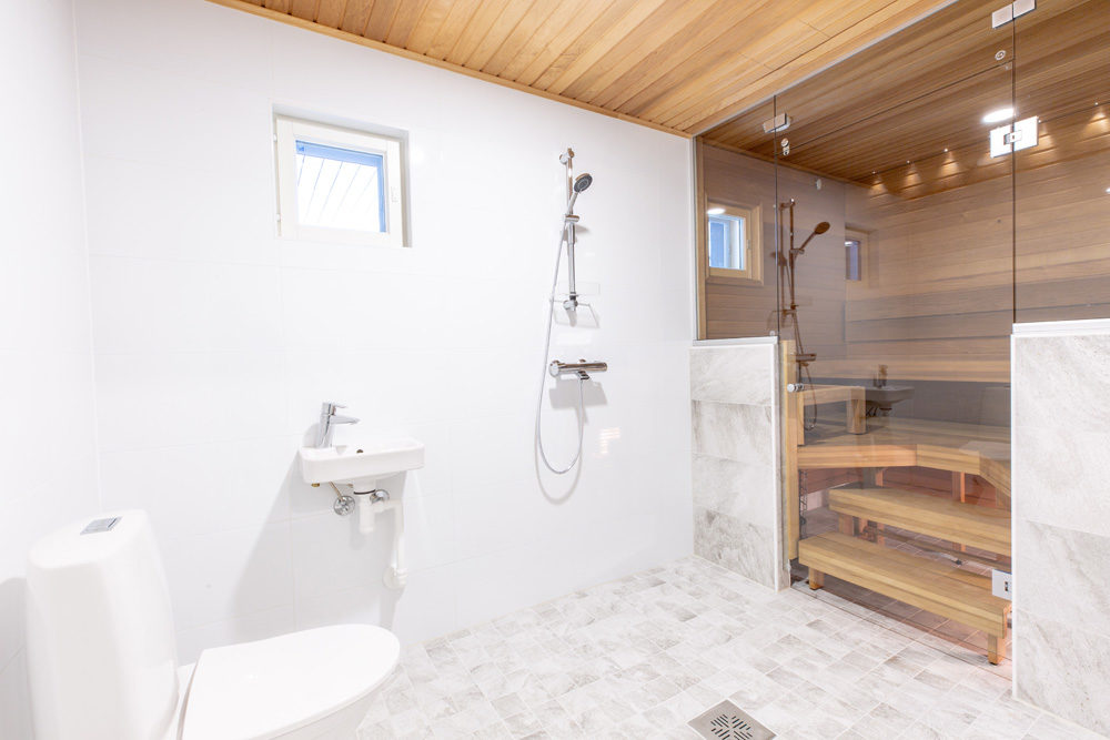 Kylpyhuone ja sauna yhdistyvät lasin avulla avaraksi tilaksi.