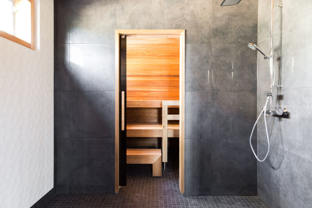 Arkkitehdin suunnittelema omakotitalo: Kylpyhuoneessa näkyy kodin sävymaailma: valkoinen, tummanharmaa ja puunsävy.