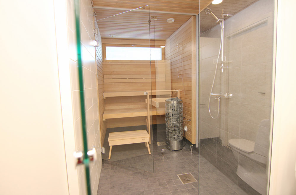 Lasiseinät erottavat saunan, kylpy- ja kodinhoitohuoneen toisistaan.