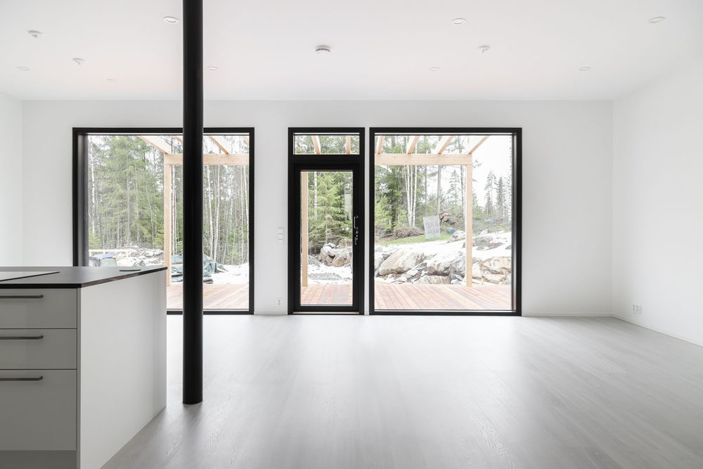 Kaksikerroksinen talo: Isot ikkunat avautuvat metsäiseen luontoon.