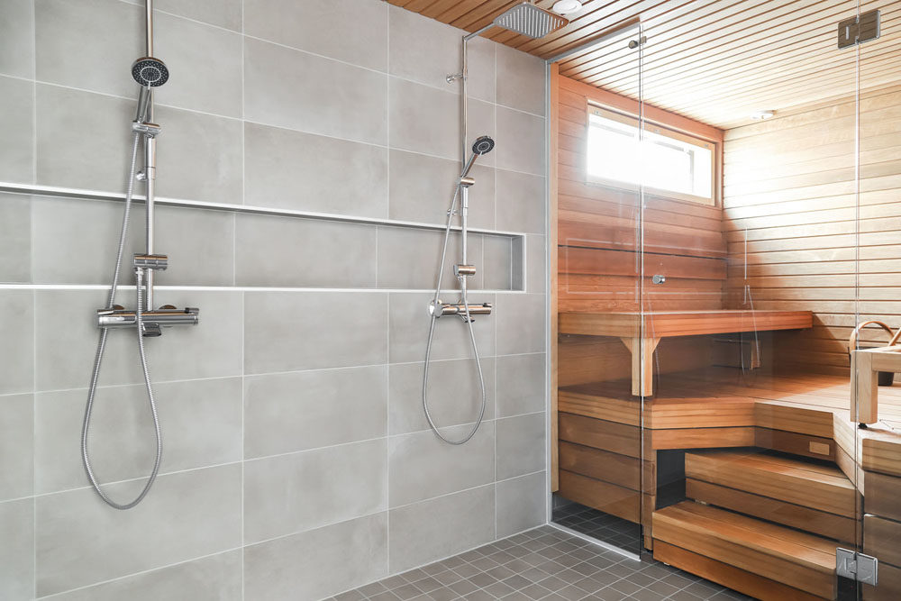 Kaksikerroksinen talo: Lasiseinä yhdistää saunan ja pesuhuoneen yhdeksi tilaksi.